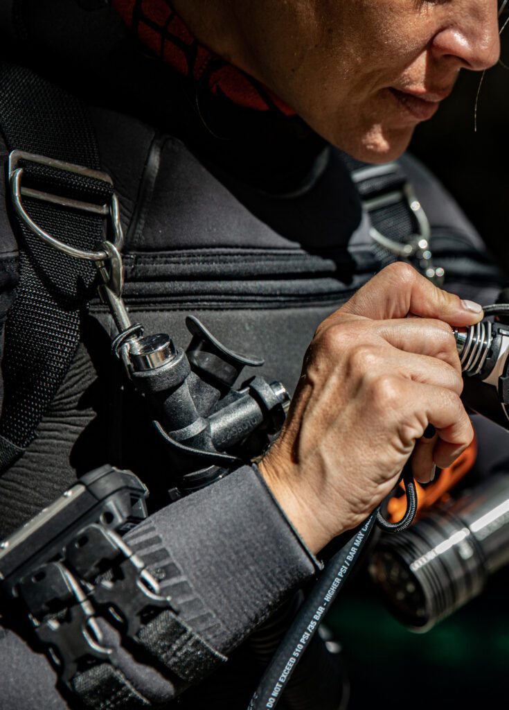 Diver checking hoses and attachment points on a worn technical diving kit