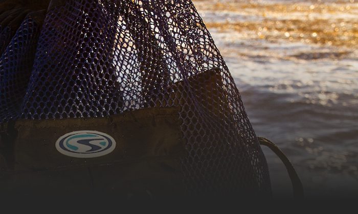 Stahlsac mesh gear bag beside a rocky shoreline